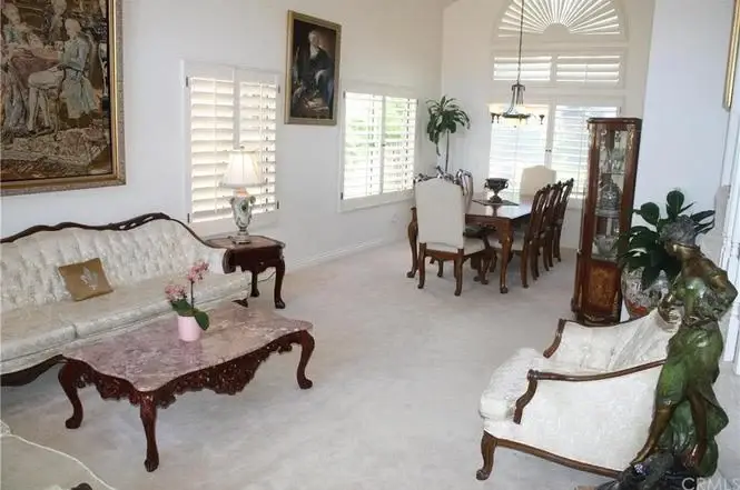 Living room with cream sofa, marble coffee table, dining area, and windows