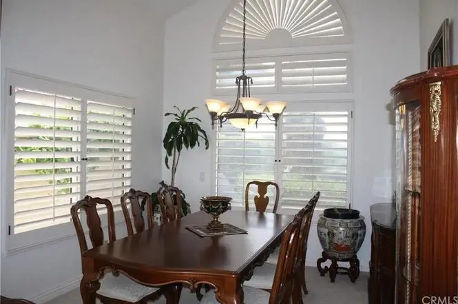 Dining room with wooden table, chairs, chandelier, windows and plant