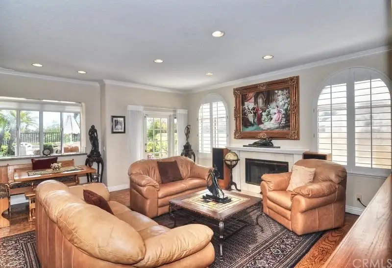 Living room with light sofas, hardwood floors, painting, large windows, and dining area