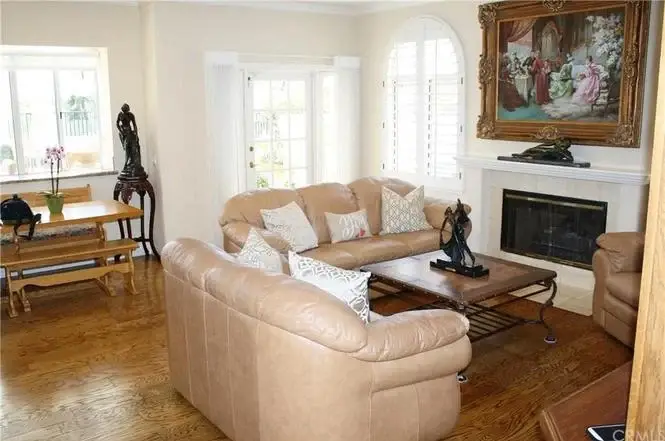 Living room with beige couch, wooden coffee table, fireplace, dining table, and artwork
