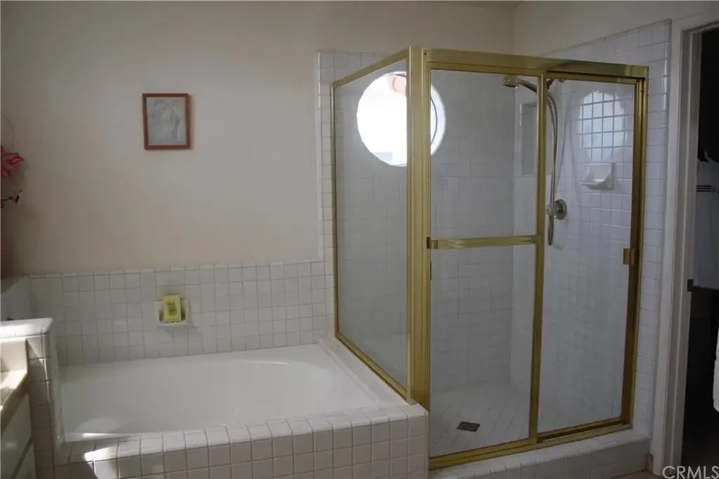 Bathroom with bathtub and glass shower enclosure with gold trim