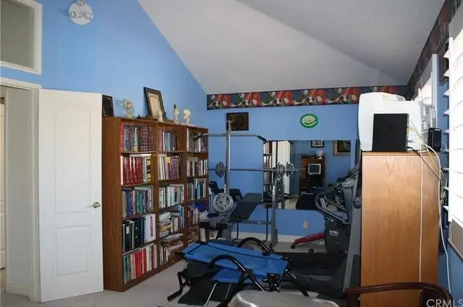 Room with blue walls, bookshelf with books, exercise equipment, and small window