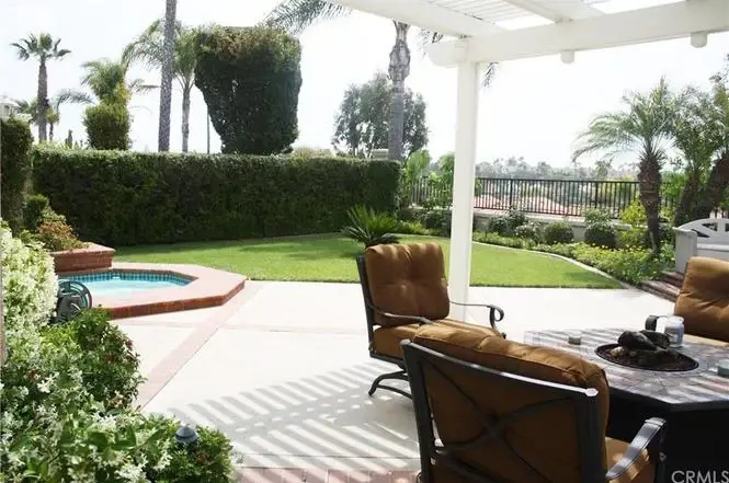 Patio with brown outdoor furniture, small pool, and greenery