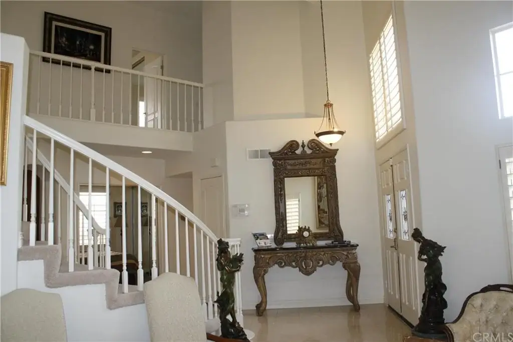 Interior of home with staircase, console table with mirror, and large windows