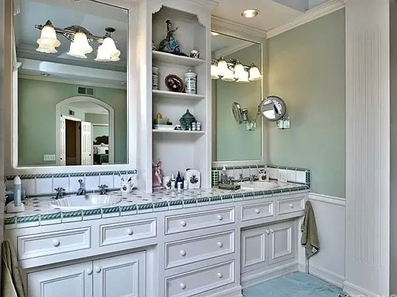 Bathroom with double vanity, white cabinets, granite countertop, sinks, green walls, and large mirror