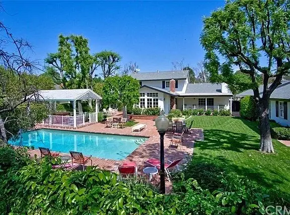 Backyard with swimming pool, lounge chairs, gazebo, and greenery