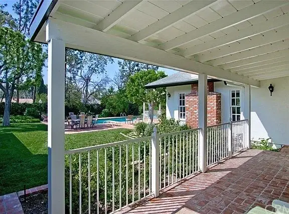 Covered porch view of backyard with pool, greenery, and trees