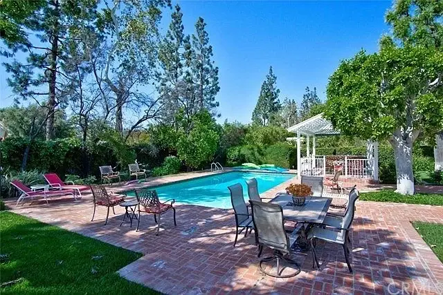 Backyard with swimming pool, greenery, lounge chairs, dining table, and gazebo