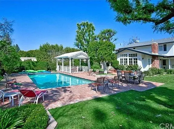 Backyard with swimming pool, trees, grass, lounge chairs, and gazebo