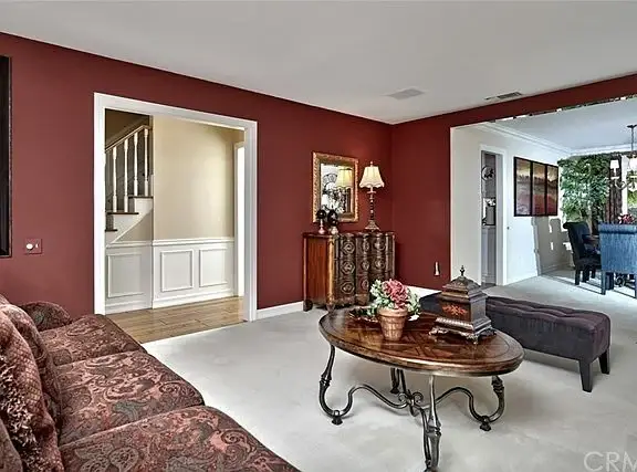 Living room with red walls, patterned sofa, coffee table, entryway, and stairs