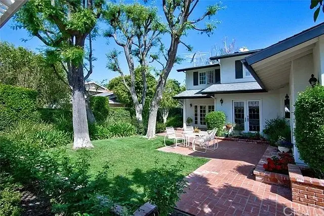 Backyard with garden, green grass, trees, brick patio, and outdoor seating