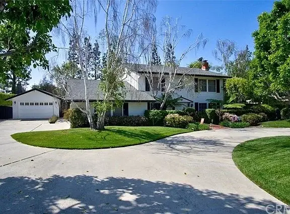 Luxury house California real estate with large front yard, landscaping, circular driveway, and detached garage