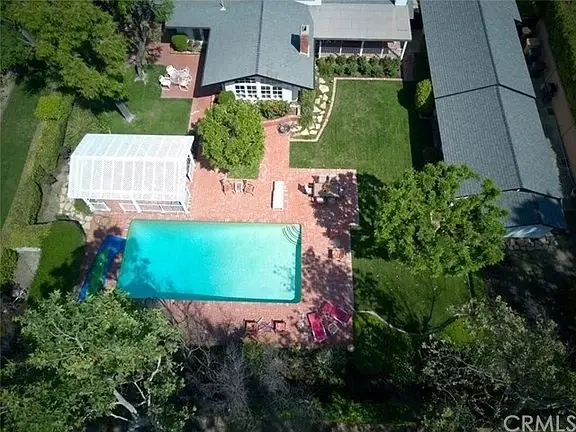 Backyard with large swimming pool, brick patios, and landscaped gardens