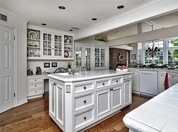 Kitchen with large white island, cabinets, wooden floor, and windows