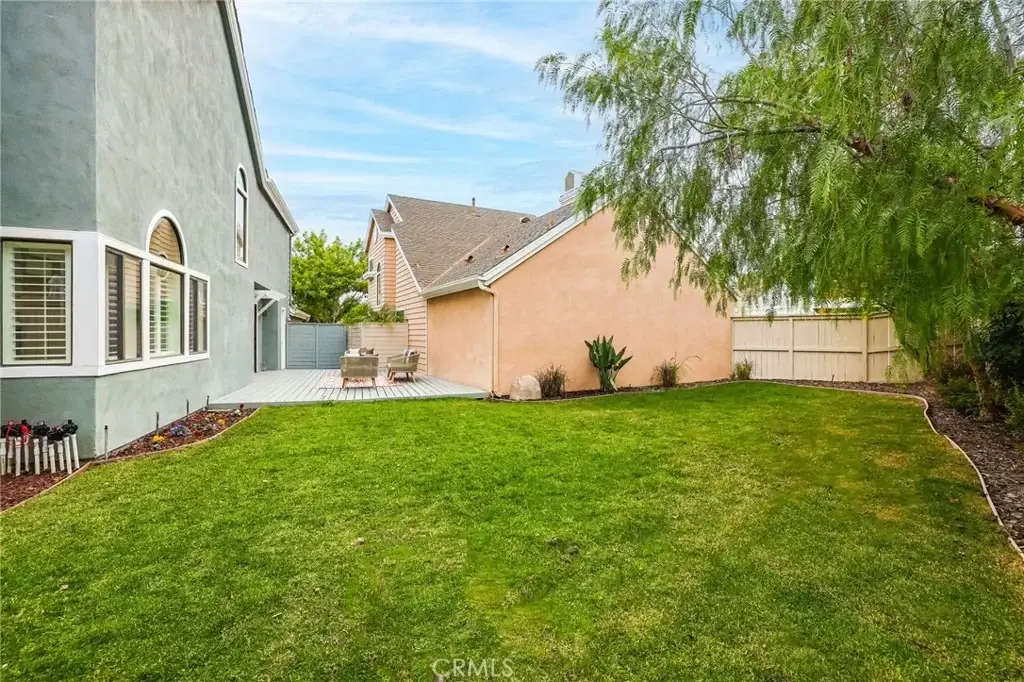 House exterior with sliding glass door, patio, mulch landscaping, plants, and green grass
