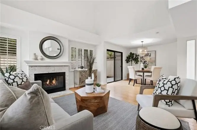 Living room with fireplace, two chairs with pillows, coffee table, and dining area with round table and chairs