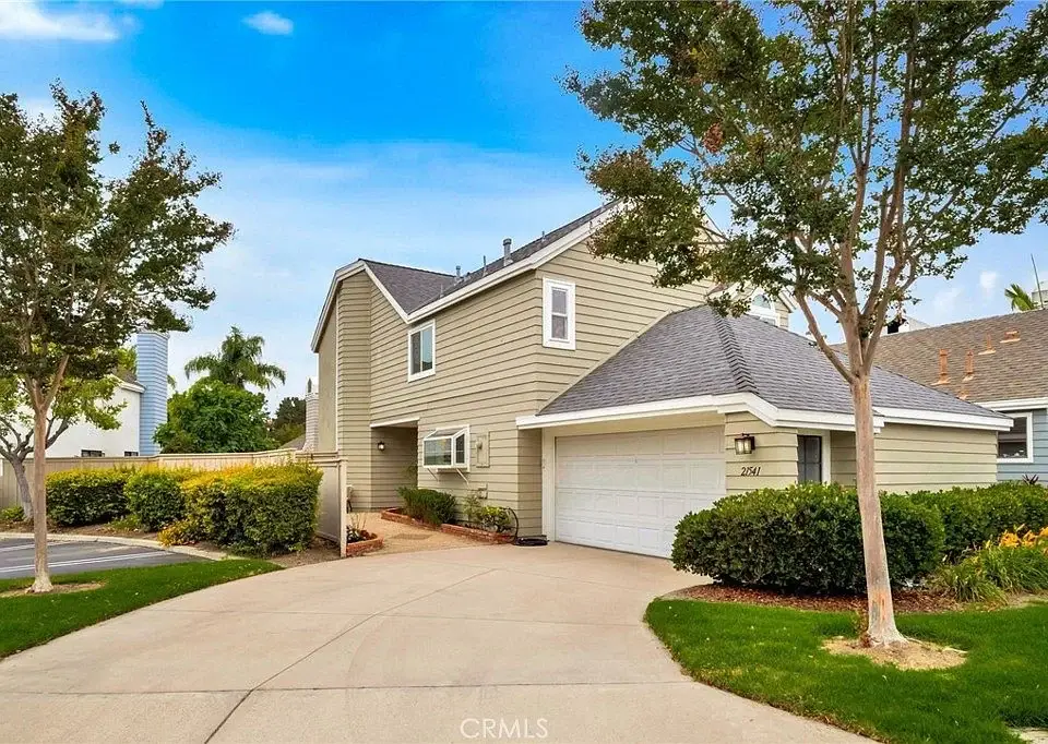 Two story house California real estate with green siding, gray roof, curved driveway, and palm trees.