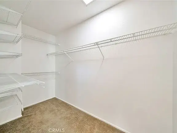 Empty closet with white wire shelves and beige carpet floor.