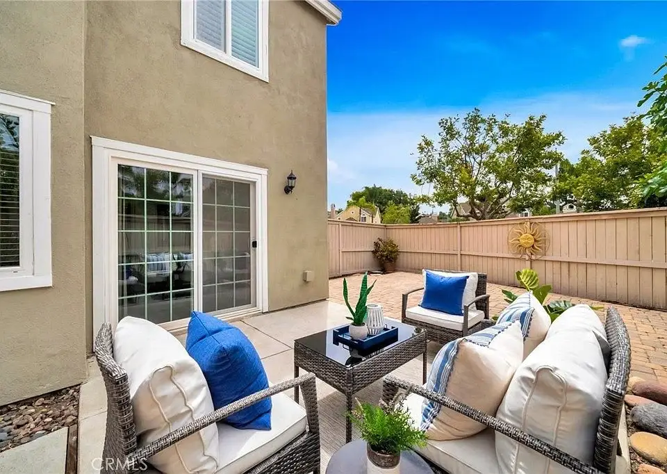 Outdoor patio with chairs, table, fence, and green plants.