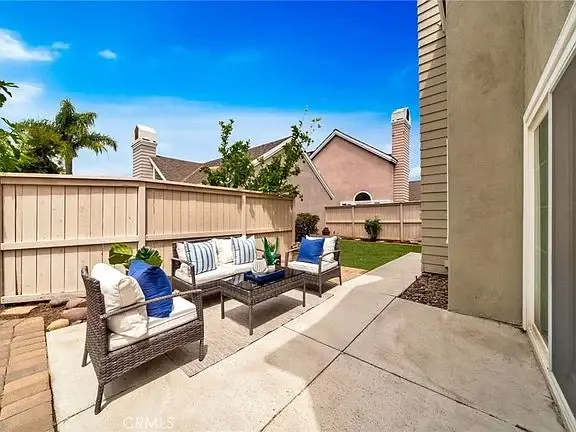 outdoor patio with wicker chairs, coffee table, blue and white cushions, and green plants