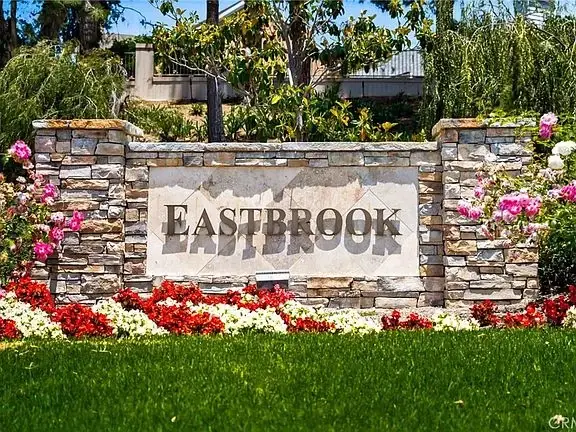 Stone sign that says EASTBROOK with flowers in a garden.