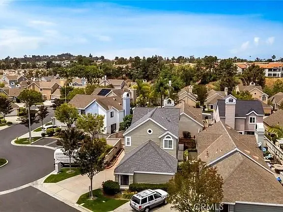 Aerial view of suburban houses California real estate with green yards and tree lined streets.