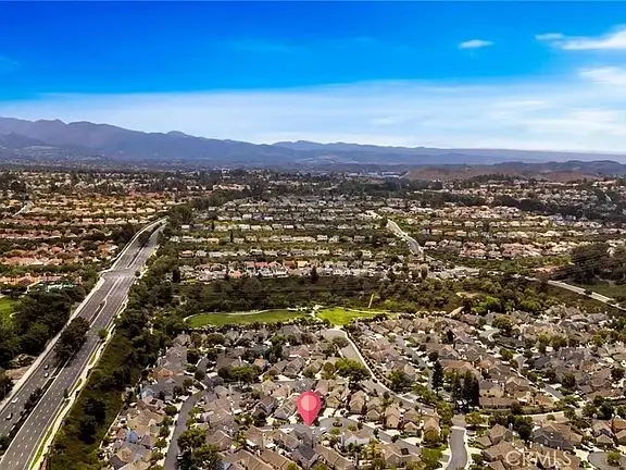 Aerial view of suburban house California real estate with roads, mountains, and a map pin on one house.