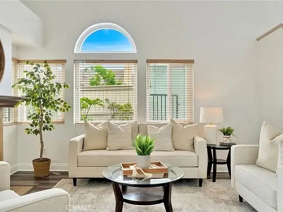 living room with light sofa, coffee table with decor, plants, and windows.