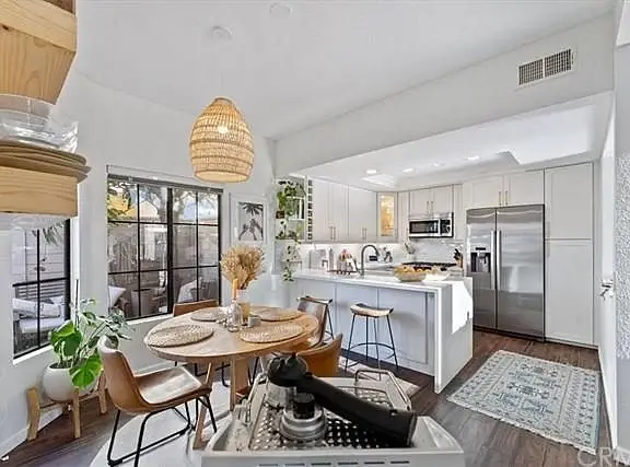 Kitchen and dining area with wooden table, chairs, plants, pendant light, and refrigerator