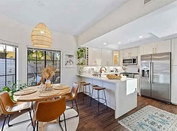 Kitchen with circular dining table, four chairs, light cabinets, window, and plants