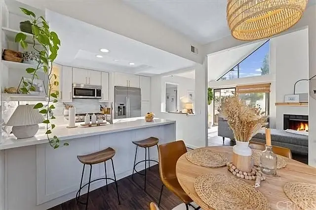 Kitchen and dining area with large island, bar stools, round table, fireplace, and plants