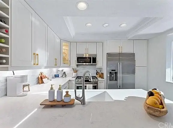 Kitchen with white cabinets, stainless steel appliances, and large island with fruit bowl