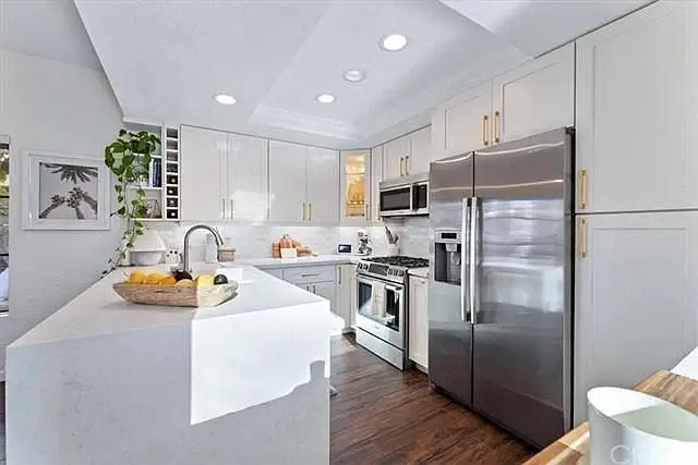 Kitchen with white cabinets, stainless steel appliances, and large island with fruit basket