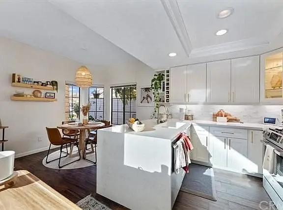 Kitchen with white cabinets, large island with sink, and dining area with round table and chairs