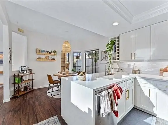 Kitchen with white cabinets, large island, and dining area with round table and chairs