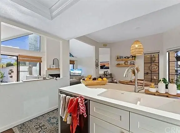 Kitchen with large island, sink, wooden accents, pendant light, and shelves with accessories