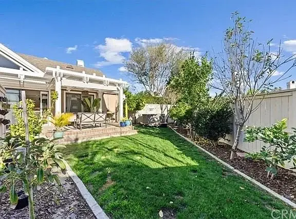 Backyard with lawn, trees, and patio next to house
