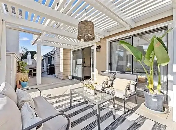 Outdoor seating area with furniture, striped rug, and potted plants
