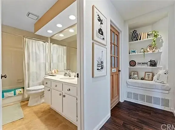 Bathroom with white vanity, mirror, shower curtain, and small shelf nook