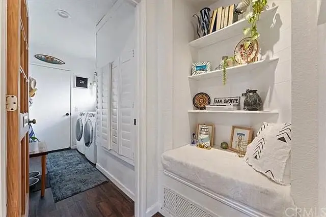 Hallway with wood floor, bench, wall shelves, and laundry