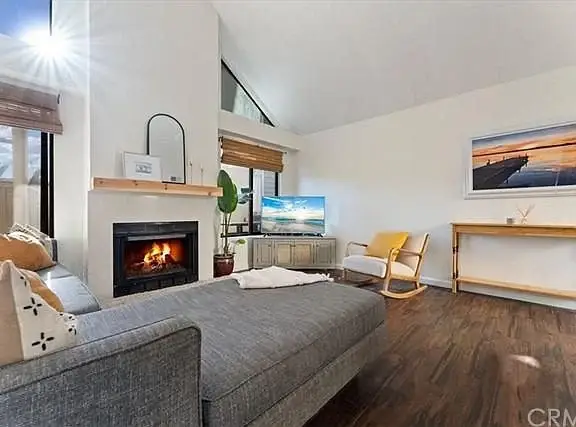 Living room with gray sectional sofa, fireplace, TV, rocking chair, and small wooden table