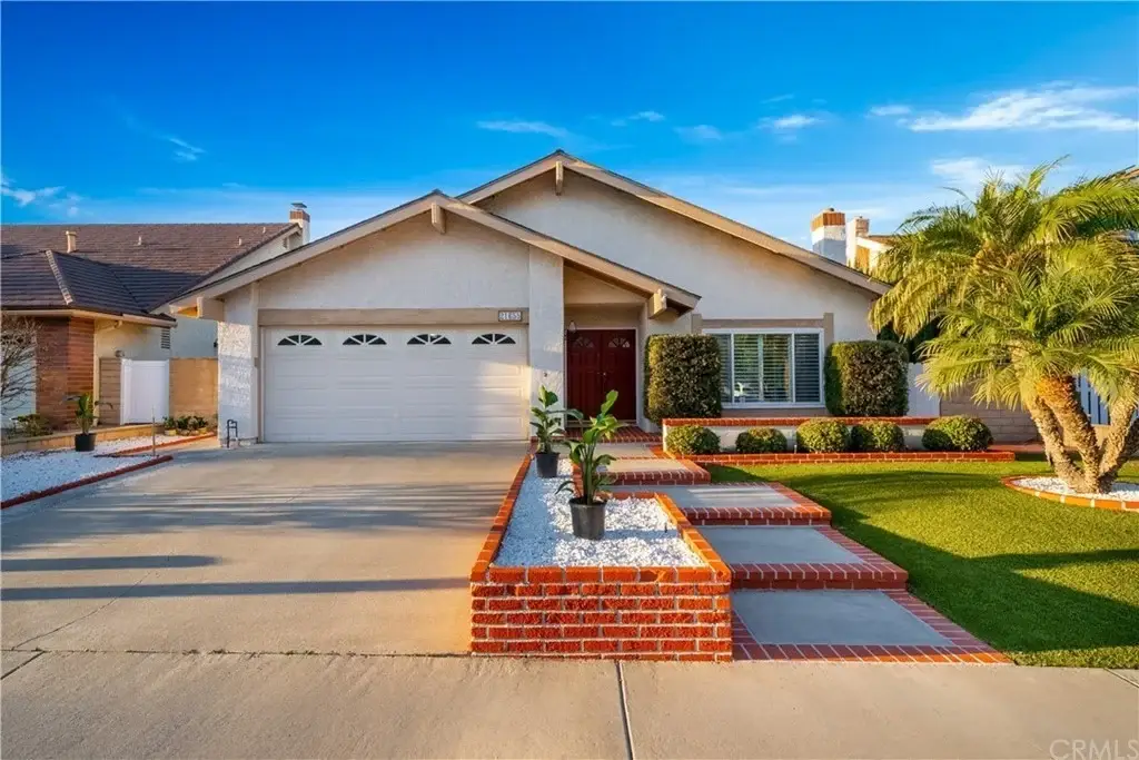 California real estate house with driveway, green lawn, tiled roof, and landscaped front yard