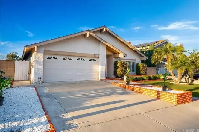 California real estate house with two-car garage, driveway, palm trees, and landscaped front yard