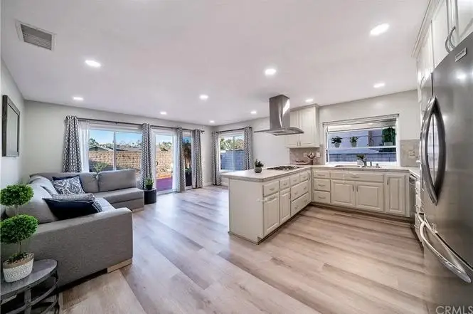 Kitchen with white cabinets, stainless steel appliances, large window, and tiled countertop