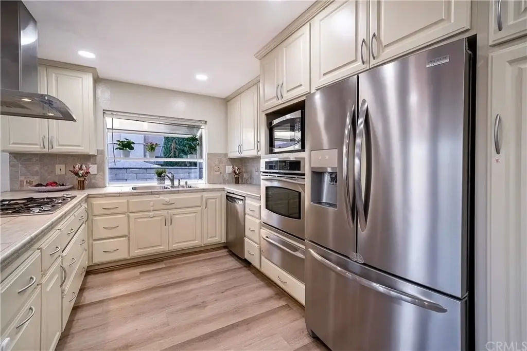 Kitchen with light cabinets, stainless steel appliances, and wood-like flooring