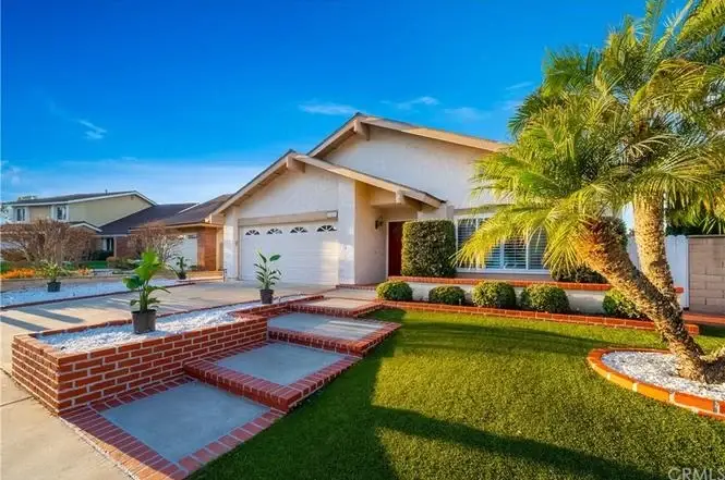 California real estate house with landscaped front yard, steps to entrance, greenery, and palm trees