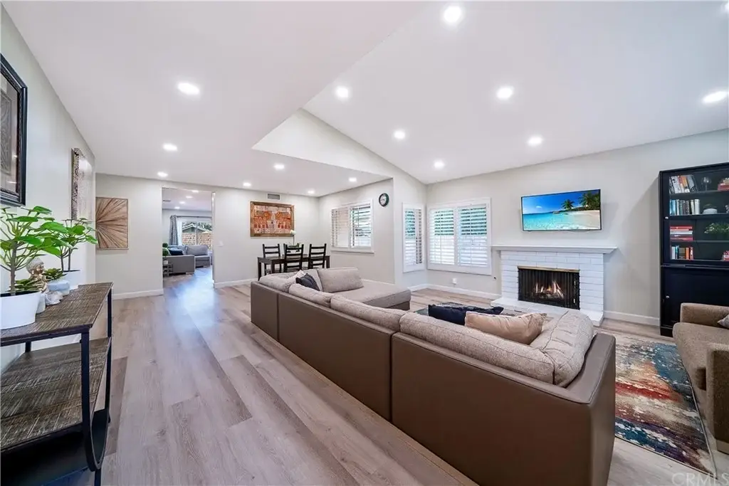 Living room with sofa, fireplace, TV, bookshelves, light wood floors