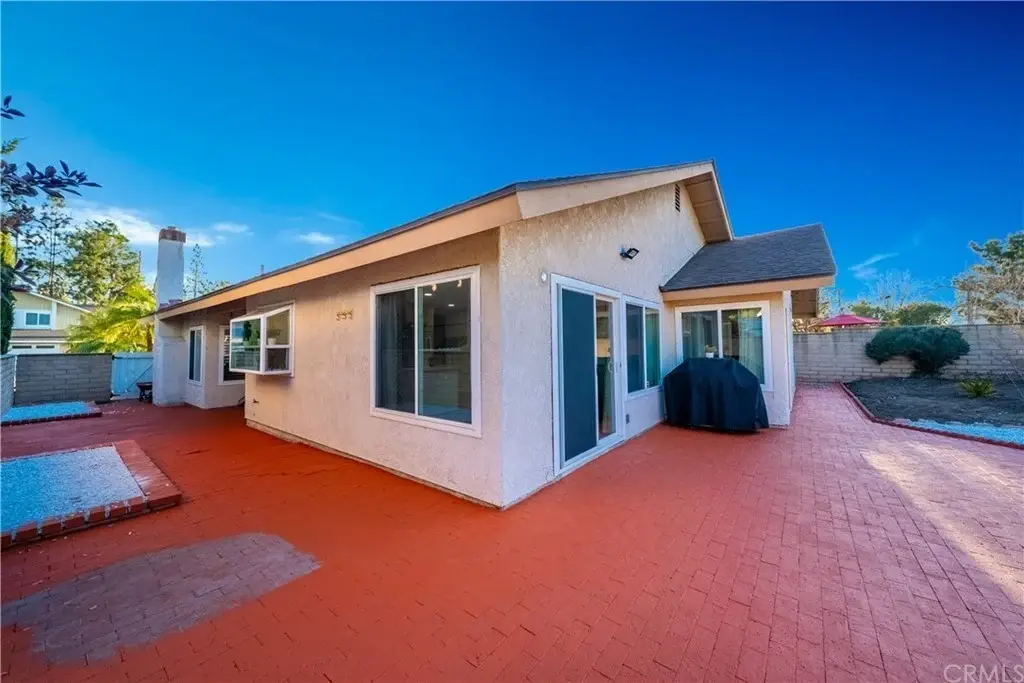 California real estate house with red-brick patio, large windows, and shaded area