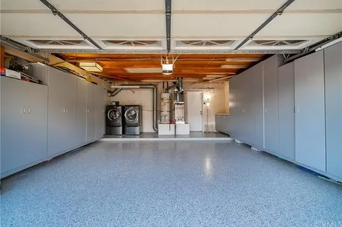 Garage with gray cabinets, two washing machines, and polished floor