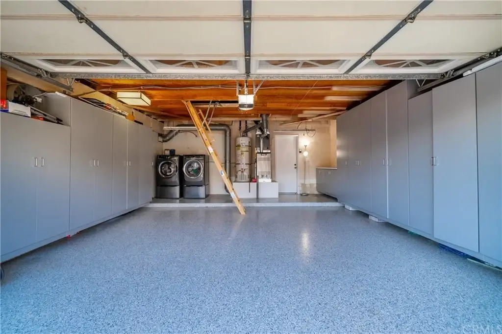 Garage with gray cabinets, stacked washer and dryer, and polished floor